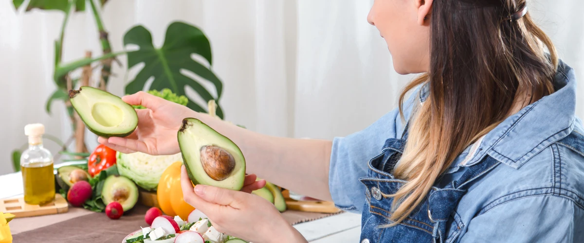 Młoda  kobieta patrząca na awokado przy stole
