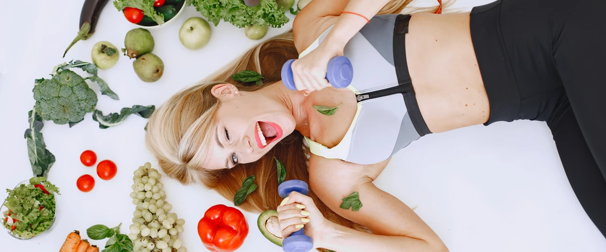 Kobieta leżąca wśród warzyw i owoców – wizualna interpretacja piramidy zdrowego żywienia.