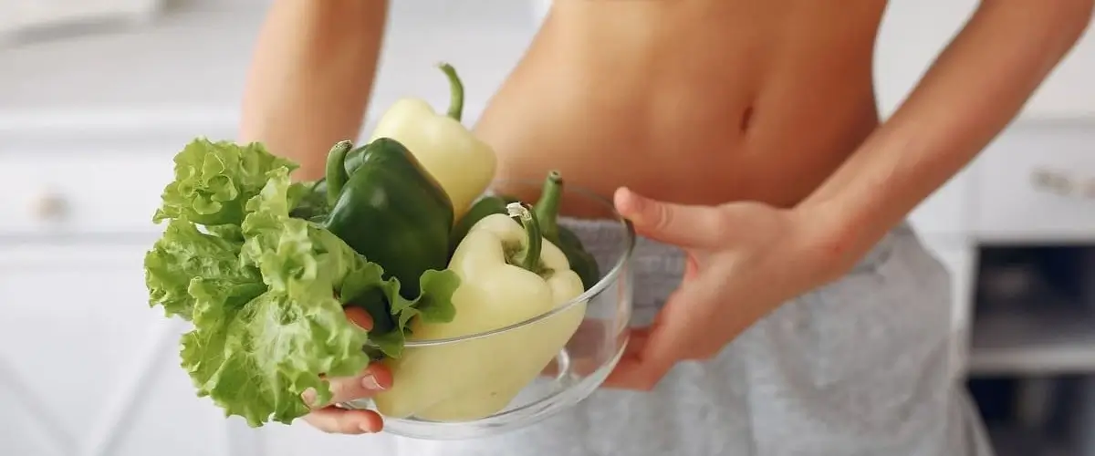 kobieta trzymająca miskę z sałatą i papryką