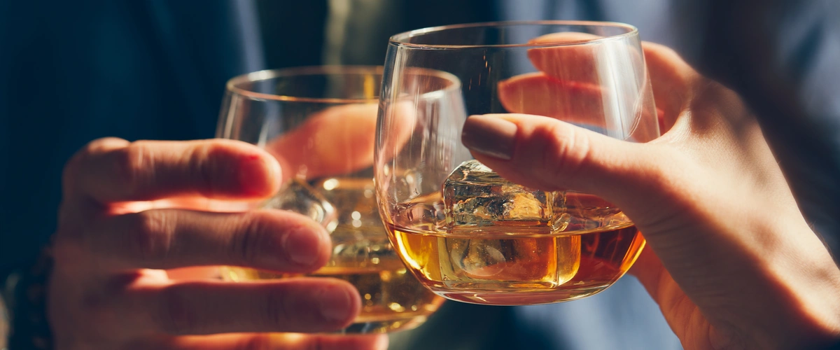 Zbliżenie na dłonie trzymające drinki w czasie toastu.