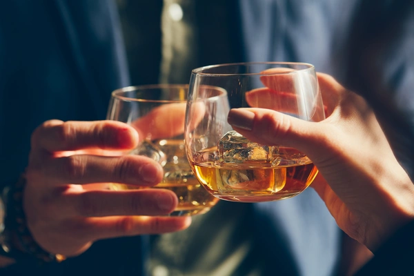 Zbliżenie na dłonie trzymające drinki w czasie toastu.