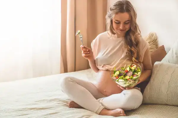 Kobieta w ciąży delektująca się sałatką warzywną