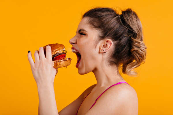 kobieta jedząca hamburgera - metabolizm