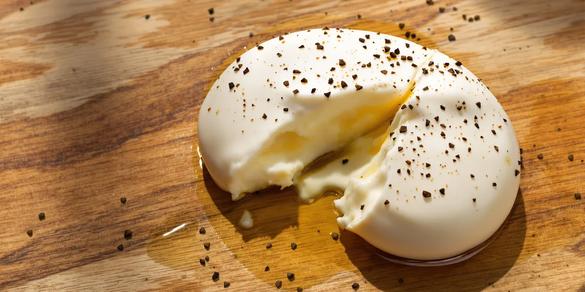 przekrojona burrata na drewnianej desce