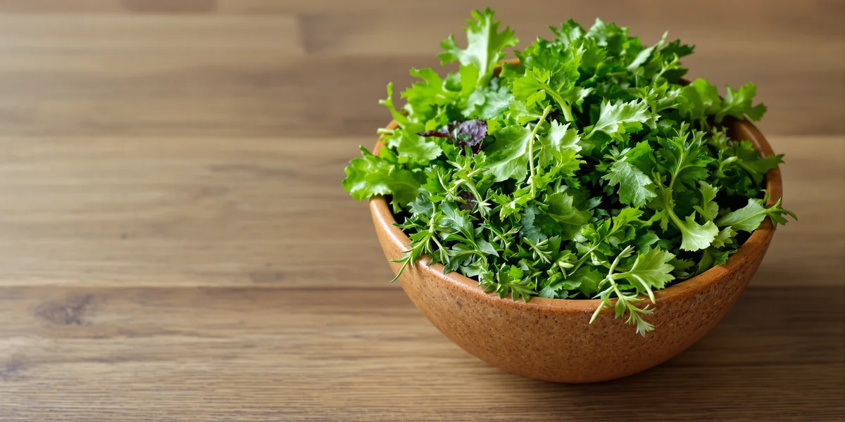 Świeże zielone liście w drewnianej misce