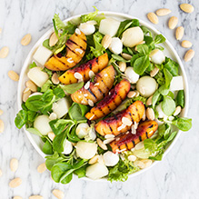 second breakfast in a vegetarian box diet - salad with grilled peach, mozzarella, melon and almonds